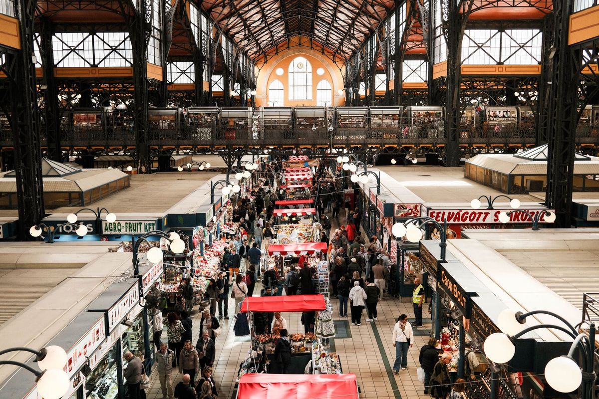 Explore the vibrant Budapest Central Market Hall filled with shoppers and vendors captured from above.